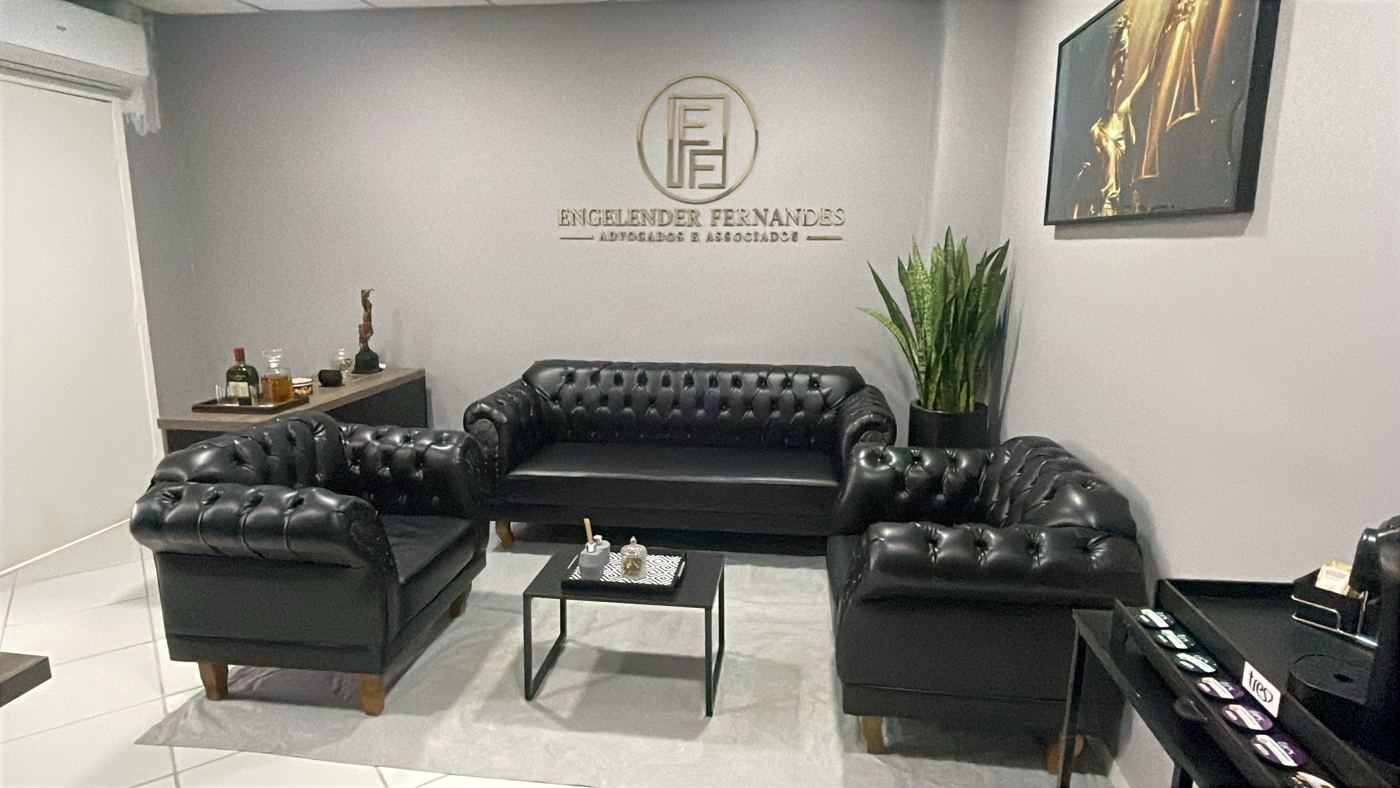 Recepção com sofás chesterfield e o logotipo do escritório na parede
