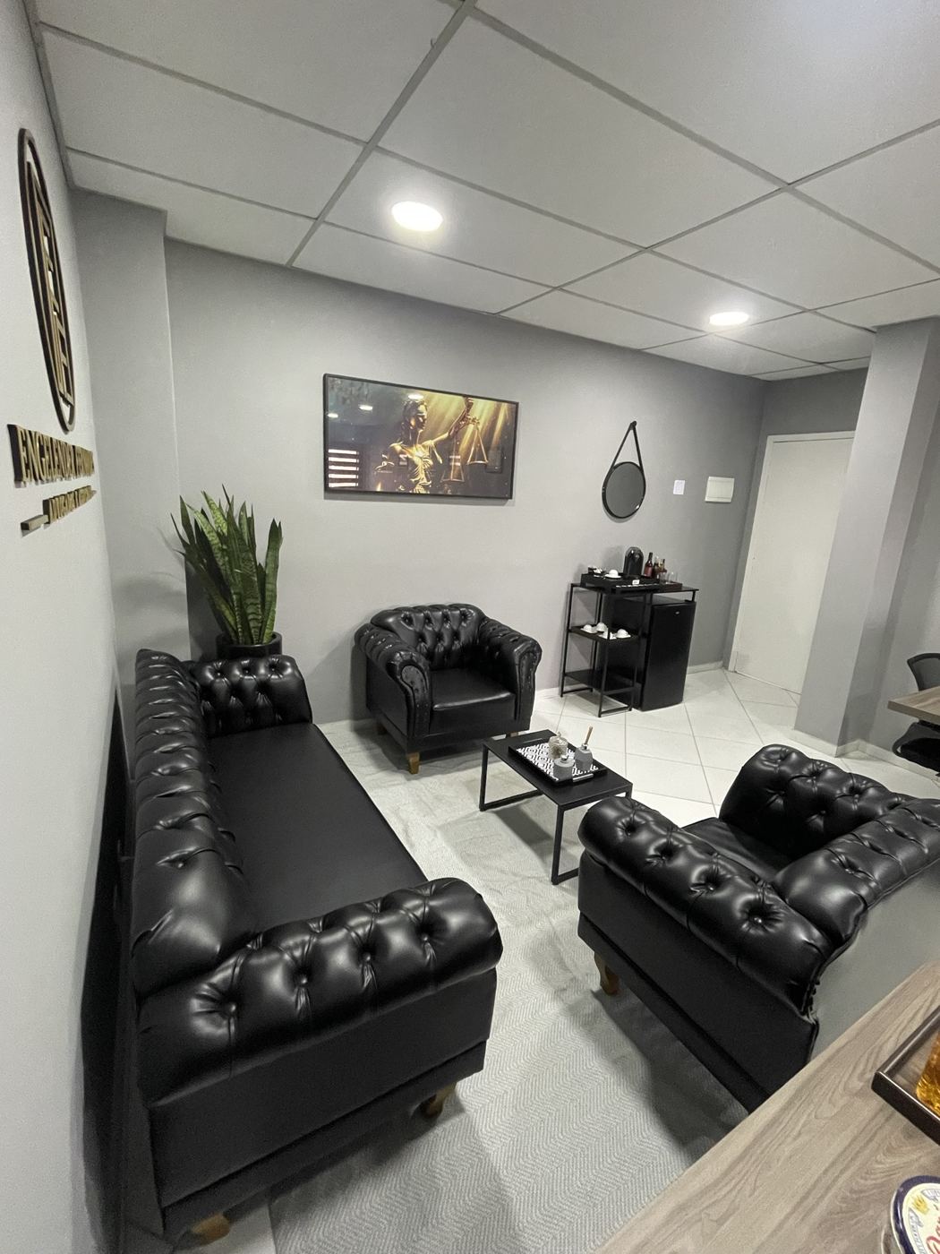 Sala de espera com sofá, poltronas e quadro da Justiça